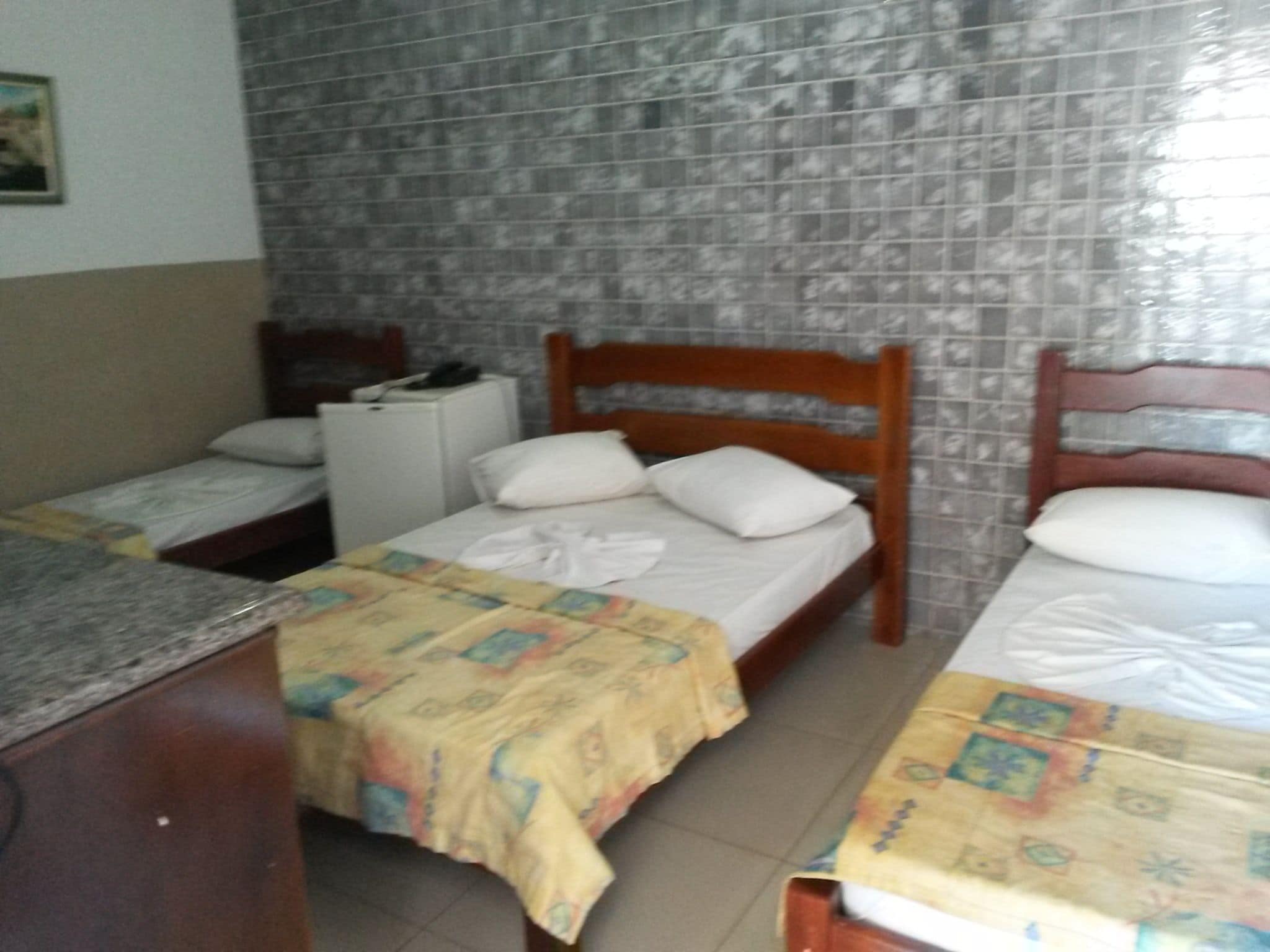 A room with two beds, a small desk, and a refrigerator.