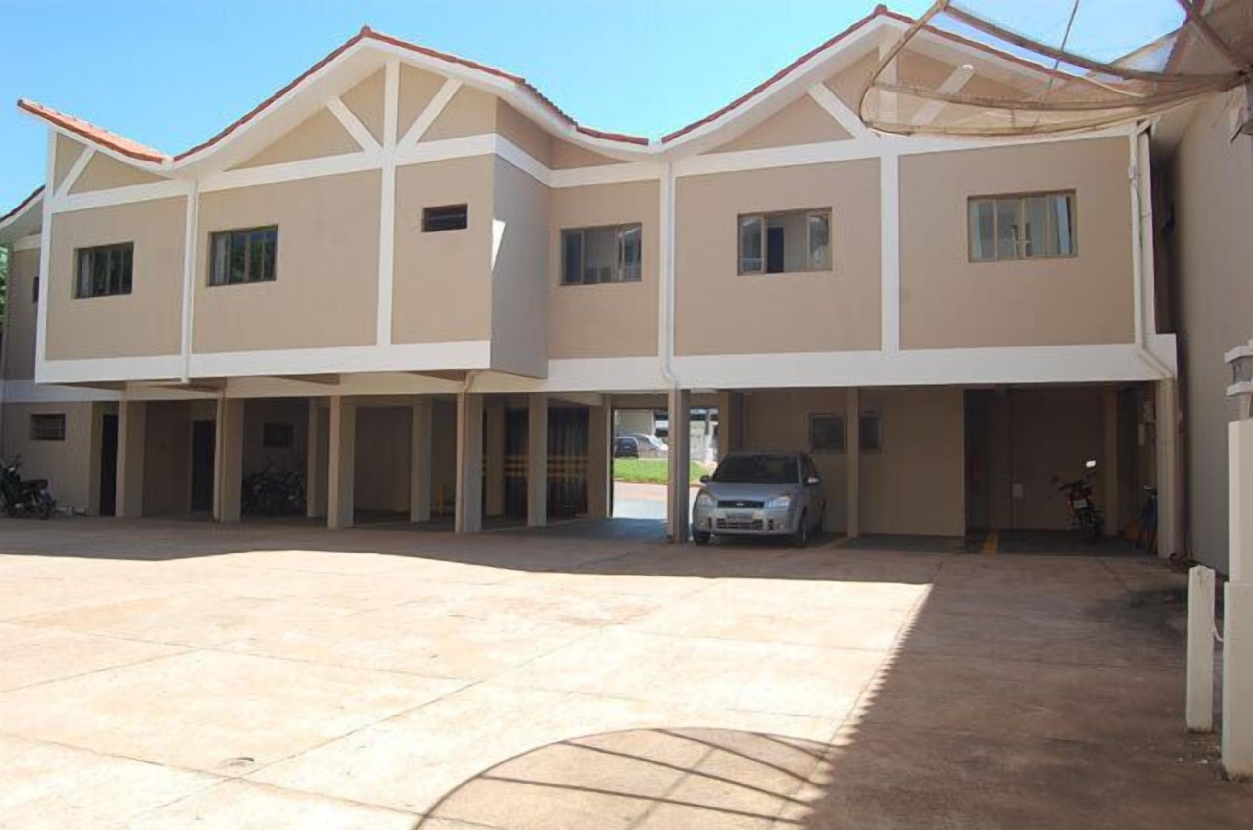 A multi-story building with a flat roof and a covered parking area.