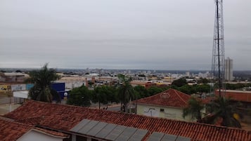 A cityscape with a mix of residential and commercial buildings, a prominent communication tower, and a variety of rooftops including solar panels.
