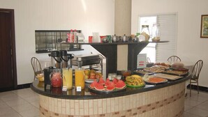 Ein Buffetbereich mit verschiedenen Speisen und Getränken, eine Kaffeestation und eine große Säule in der Mitte.
