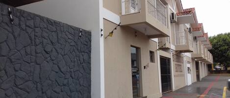 A hotel with a stone facade, balconies with metal railings, and a red line marking on the pavement.