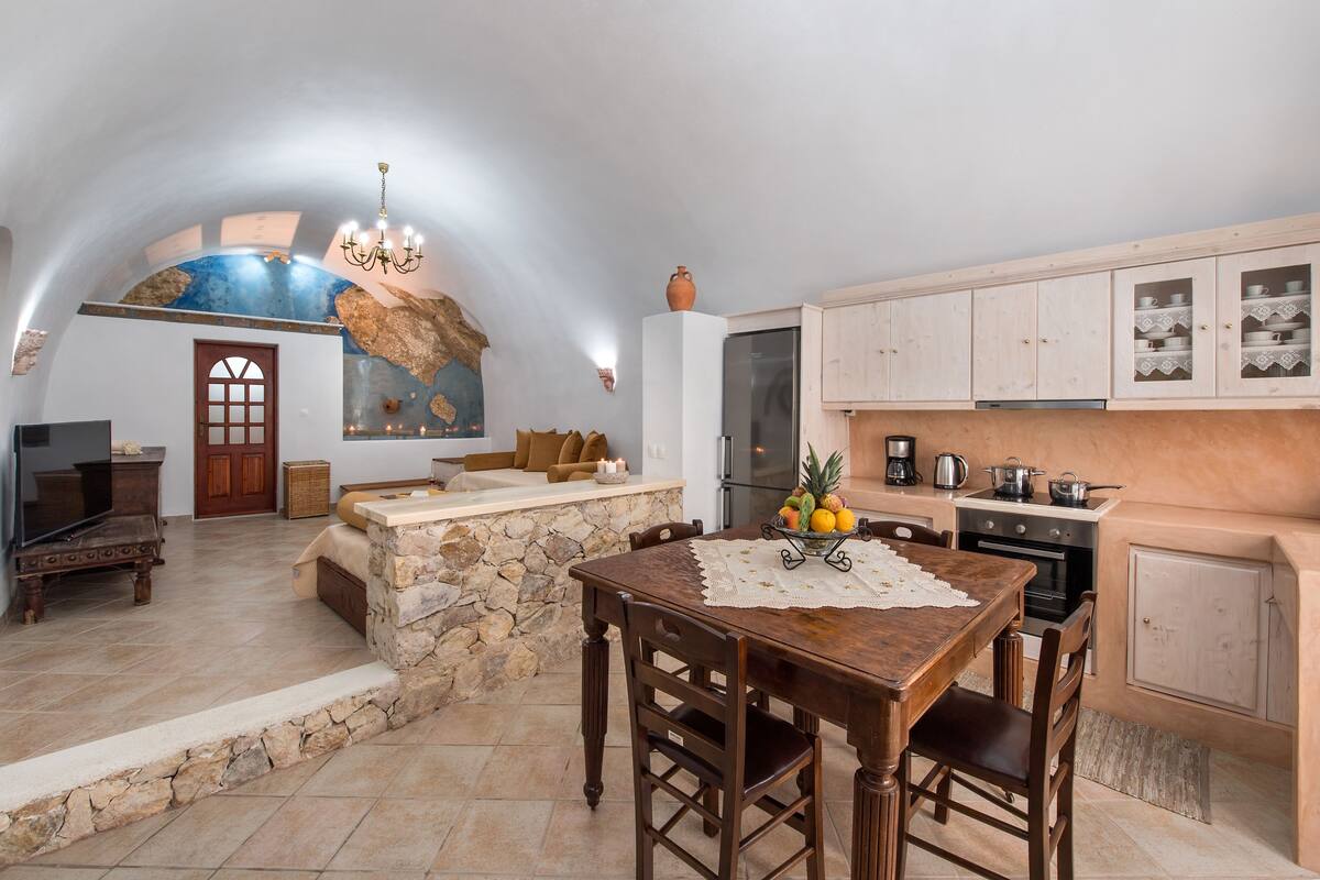 A spacious kitchen with stone accents, a dining area with a wooden table, and a cozy seating area with a stone fireplace.