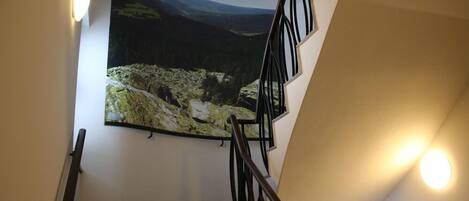 A staircase with a black railing and a large landscape painting on the wall.