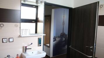 Un baño moderno con lavamanos, espejo y perchero blancos.