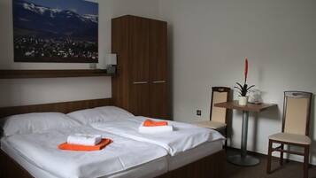 Une chambre d’hôtel avec un lit, une armoire, une petite table avec une plante et une chaise.