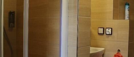 A bathroom with a glass shower enclosure, a sink, and a towel rack with a towel.
