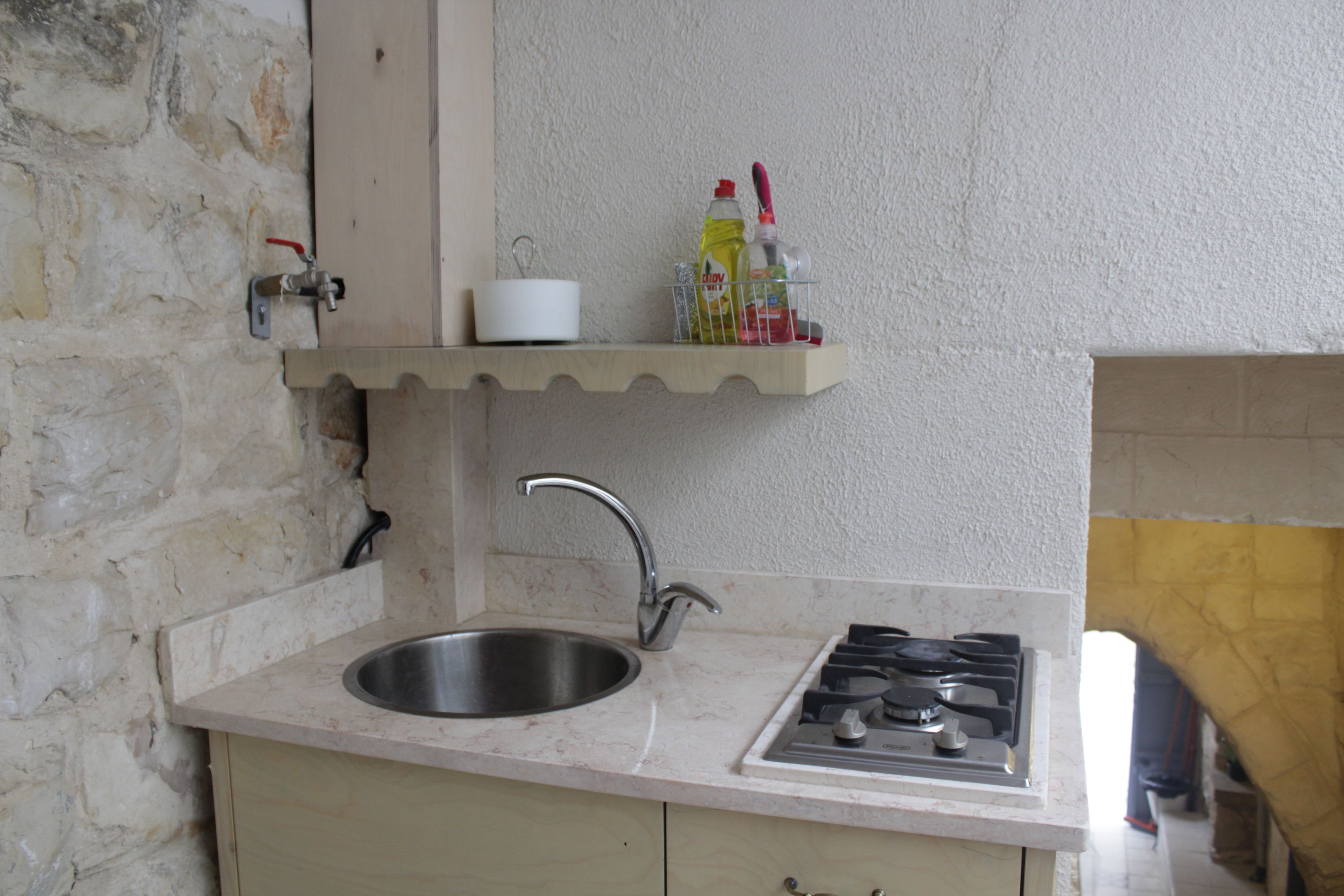 Una cocina con un lavamanos, grifo y estufa.