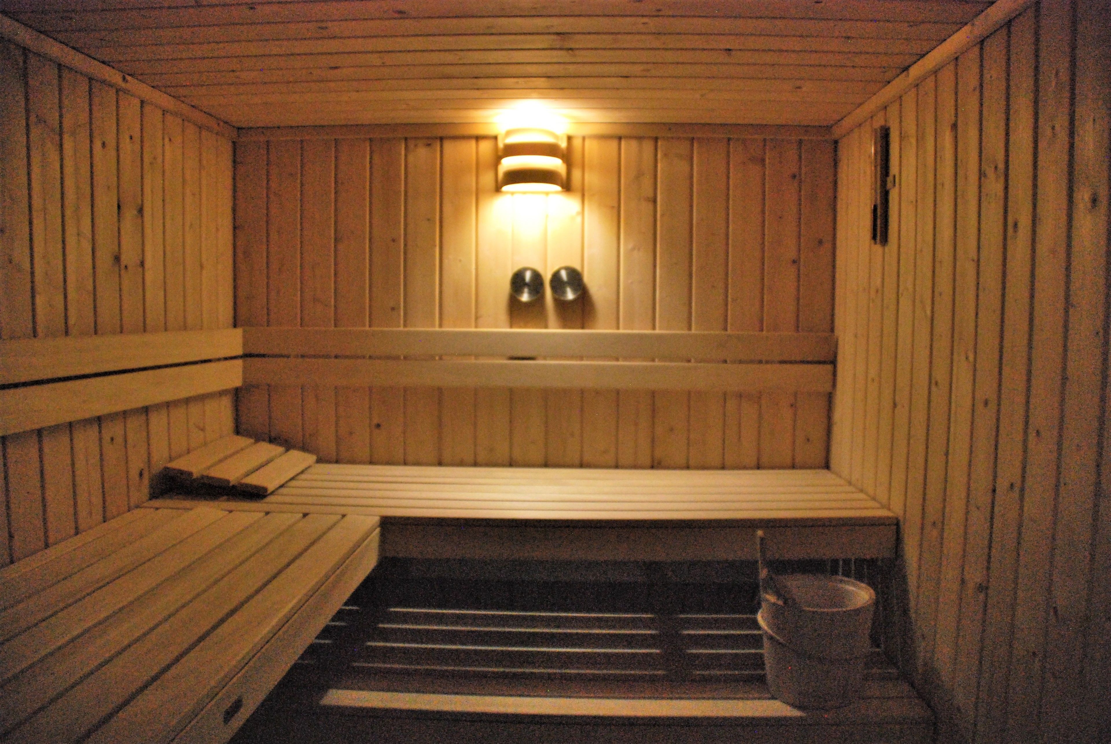 Een houten sauna met banken, inclusief een bank aan de onderkant, en een lamp boven de banken.