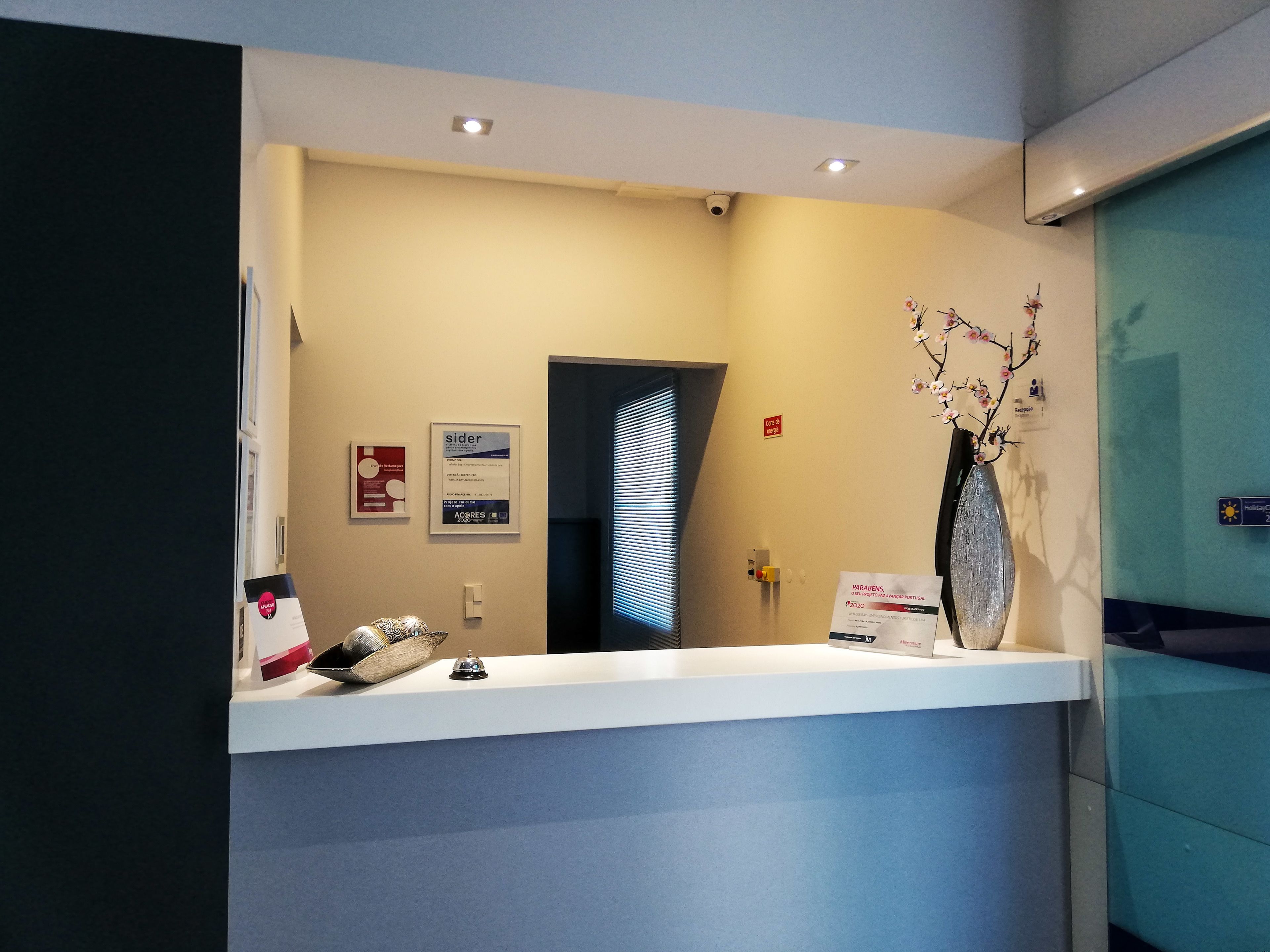 A reception desk with a white counter, a vase with flowers, and a sign indicating a conference room.