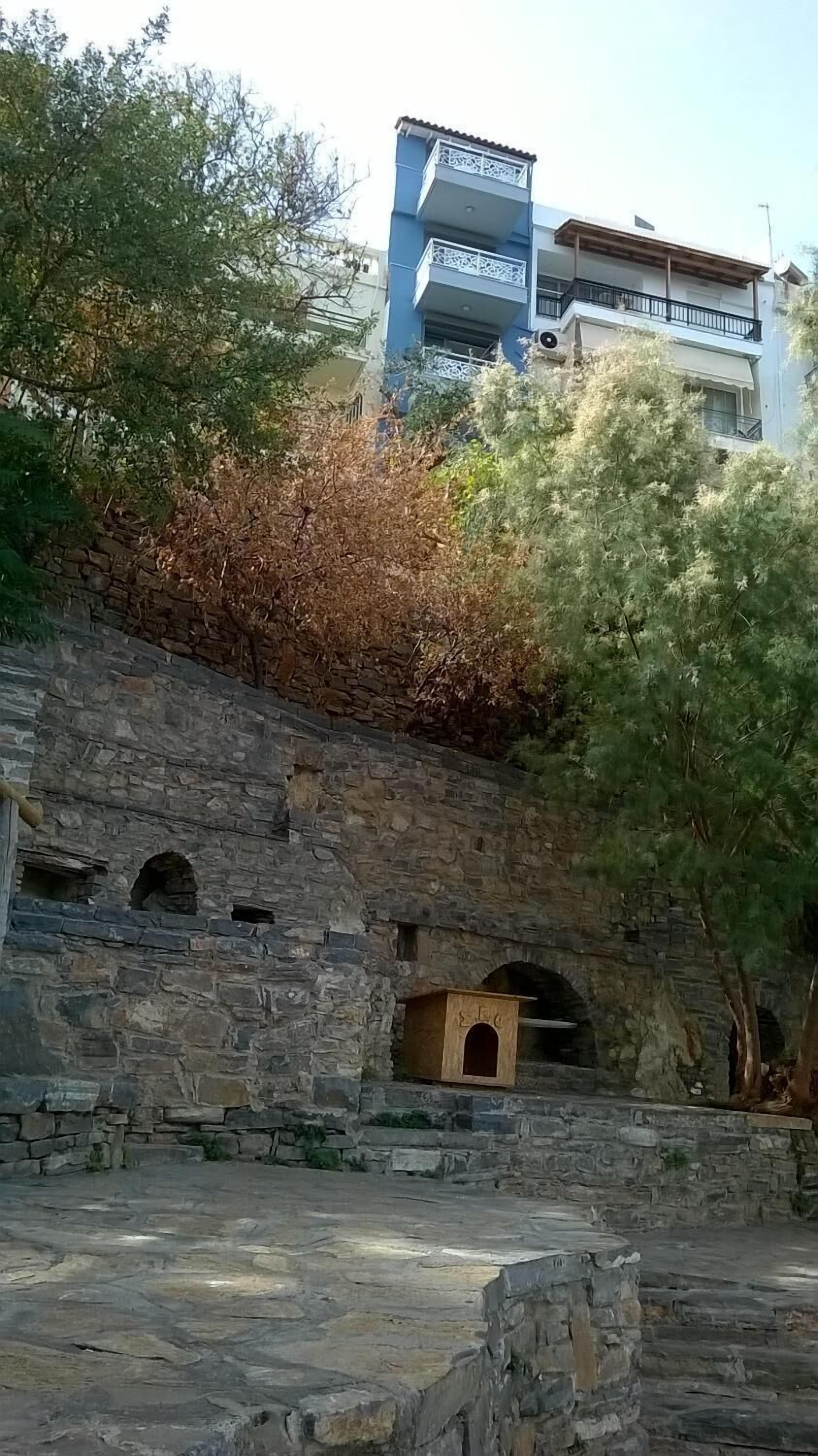 A stone structure with arched openings and a wooden box, possibly a historical site or monument.