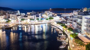 Un pueblo costero de noche con un puerto deportivo, edificios y un hotel llamado "Hotel Du Lac".