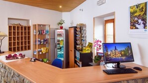 A reception area with a wooden desk, a computer, and various shelves with items. - Hotel Bella (Prague)