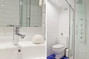 A bathroom with a white sink, mirror, and toilet, and a glass-enclosed shower area. - Blue Barcelona (Barcelona)