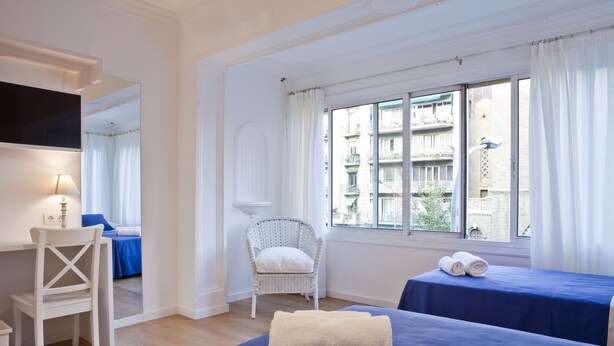 A hotel room with a bed, a chair, a desk, and a window with curtains. - Blue Barcelona (Barcelona)