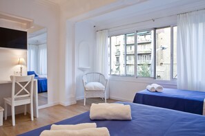 A hotel room with a bed, a chair, a desk, and a window with curtains. - Blue Barcelona (Barcelona)