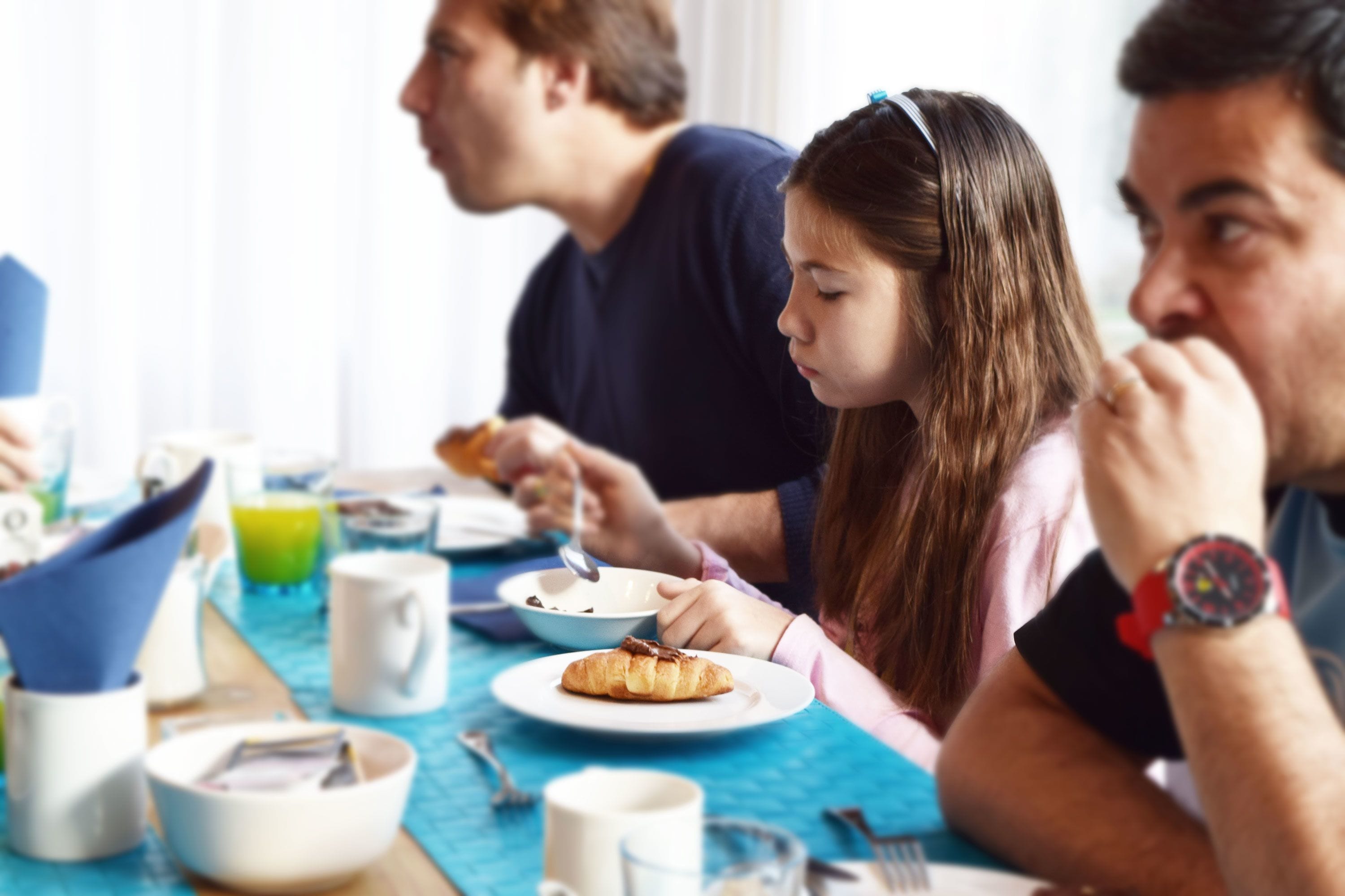 Una mesa de comedor con platos, tazas y un croissant.