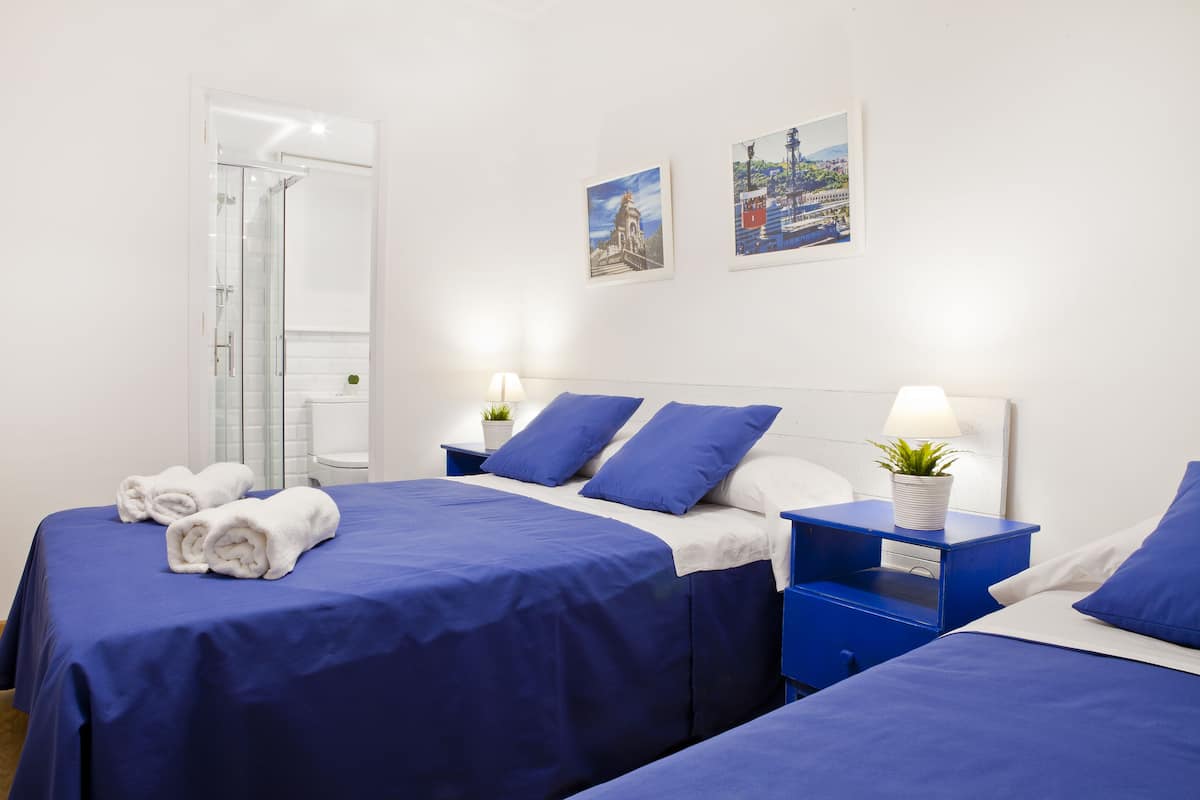 A hotel room with two beds, a glass shower, and artwork on the walls.