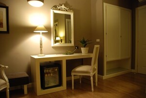 Una habitación con escritorio, silla, lámpara, espejo, planta en maceta y armario.