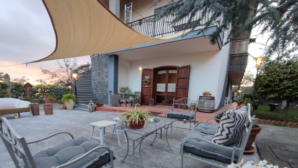 Un patio al aire libre con mobiliario, una mesa y plantas en macetas.