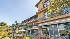 A hotel with outdoor seating, a covered patio, and a view of the surrounding landscape. - Hotel Medulio (Carucedo)