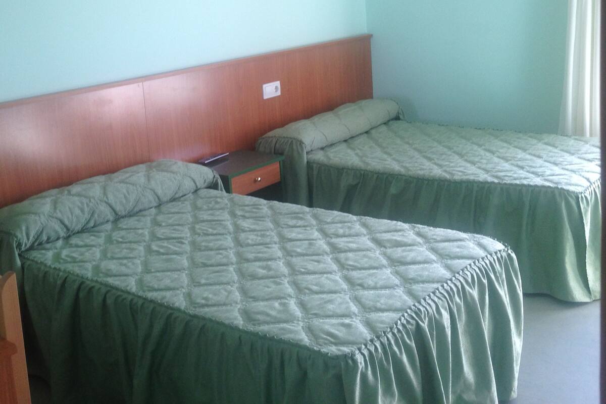 A room with two beds, a wooden headboard, a small bedside table, and a framed picture on the wall.