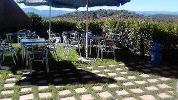 An outdoor patio with metal tables and chairs, a covered umbrella, and a fire hydrant.