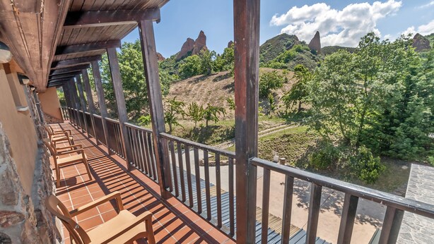 A balcony with wooden chairs and a view of a river and hills. - Hotel Medulio (Carucedo)