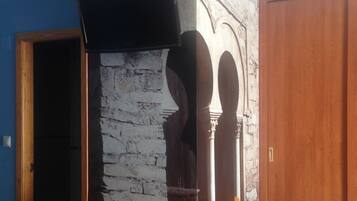 Un comedor con pared de piedra, sillas de madera y una mesa.