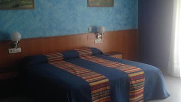 Una habitación de hotel con una cama, dos mesitas de noche, una lámpara de pared y un cuadro en la pared.