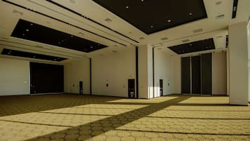 A spacious, modern hotel lobby with a patterned carpet, recessed lighting, and a high ceiling.