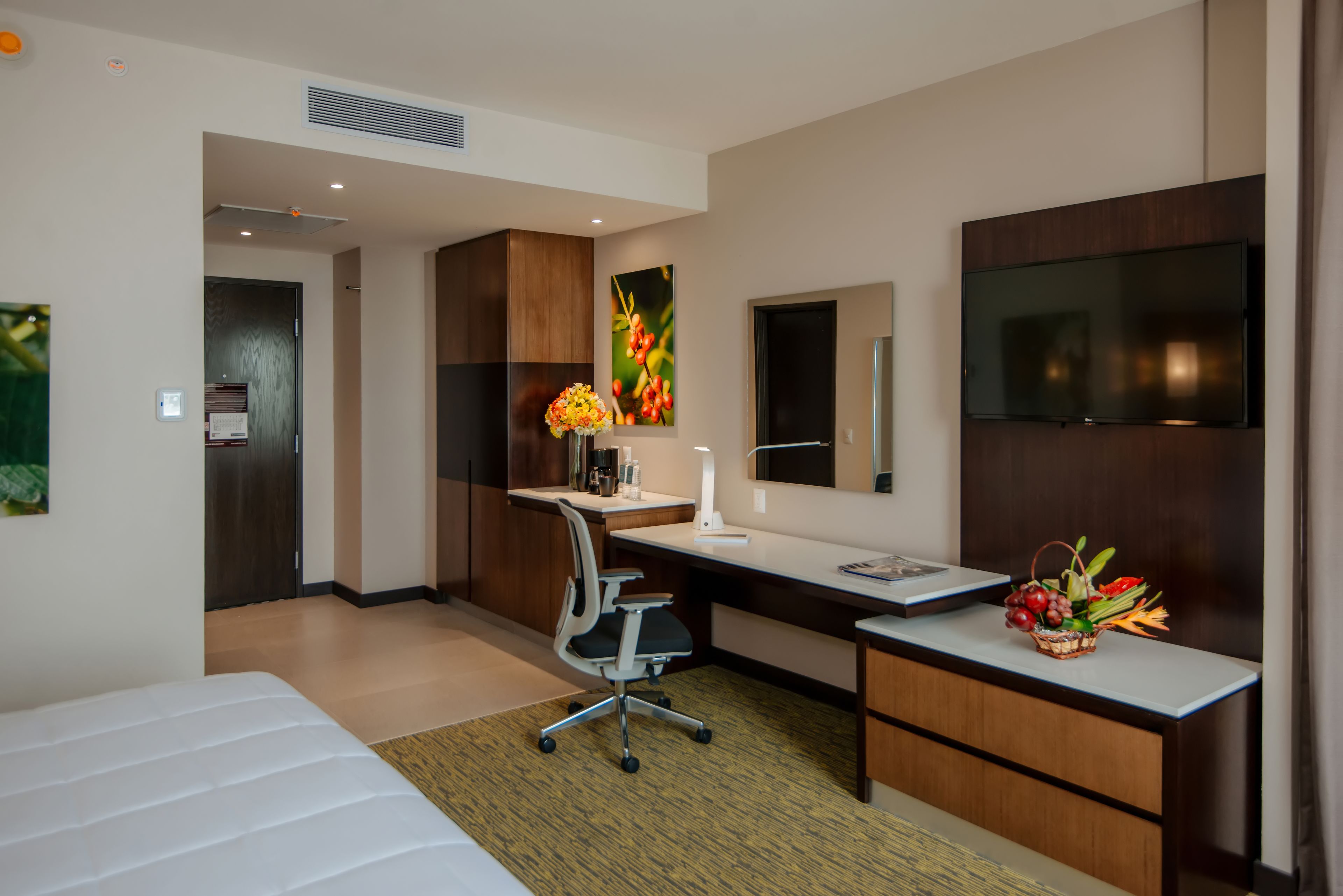 A modern hotel room with a bed, desk, and TV.