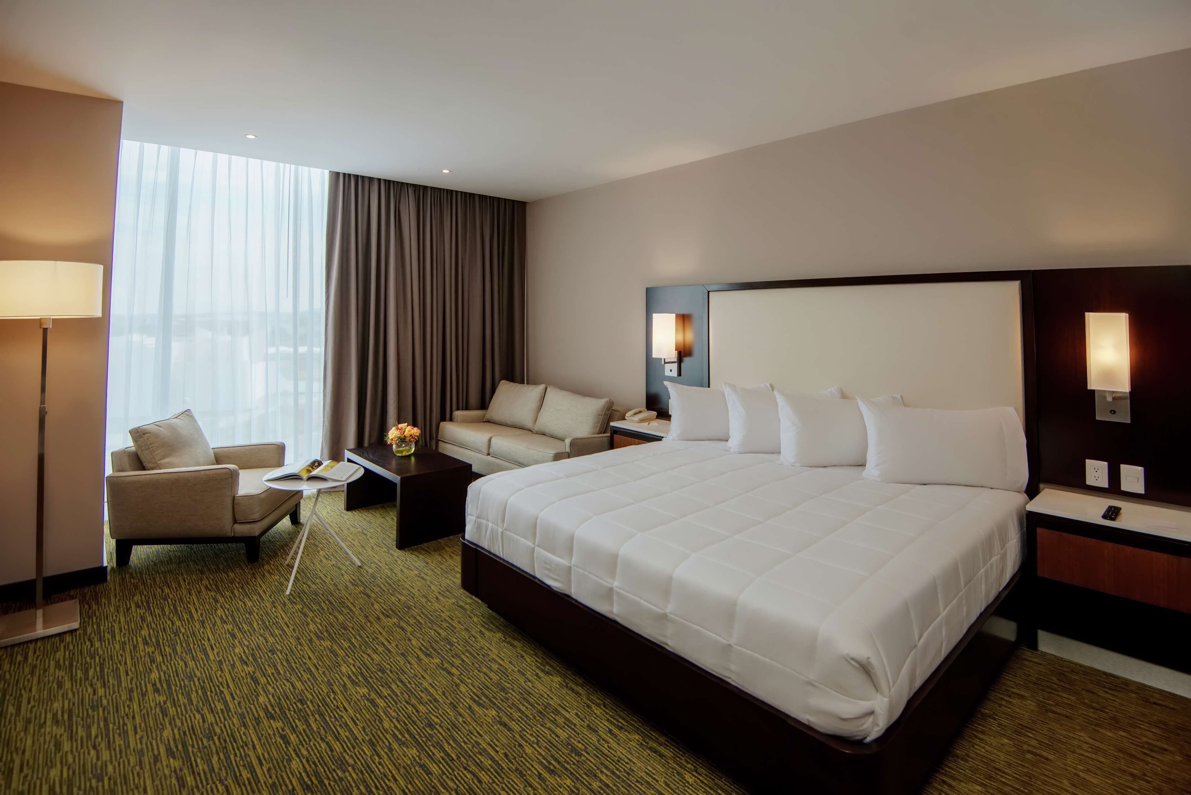 Una habitación de hotel con una cama grande, un sofá, un escritorio y una lámpara.