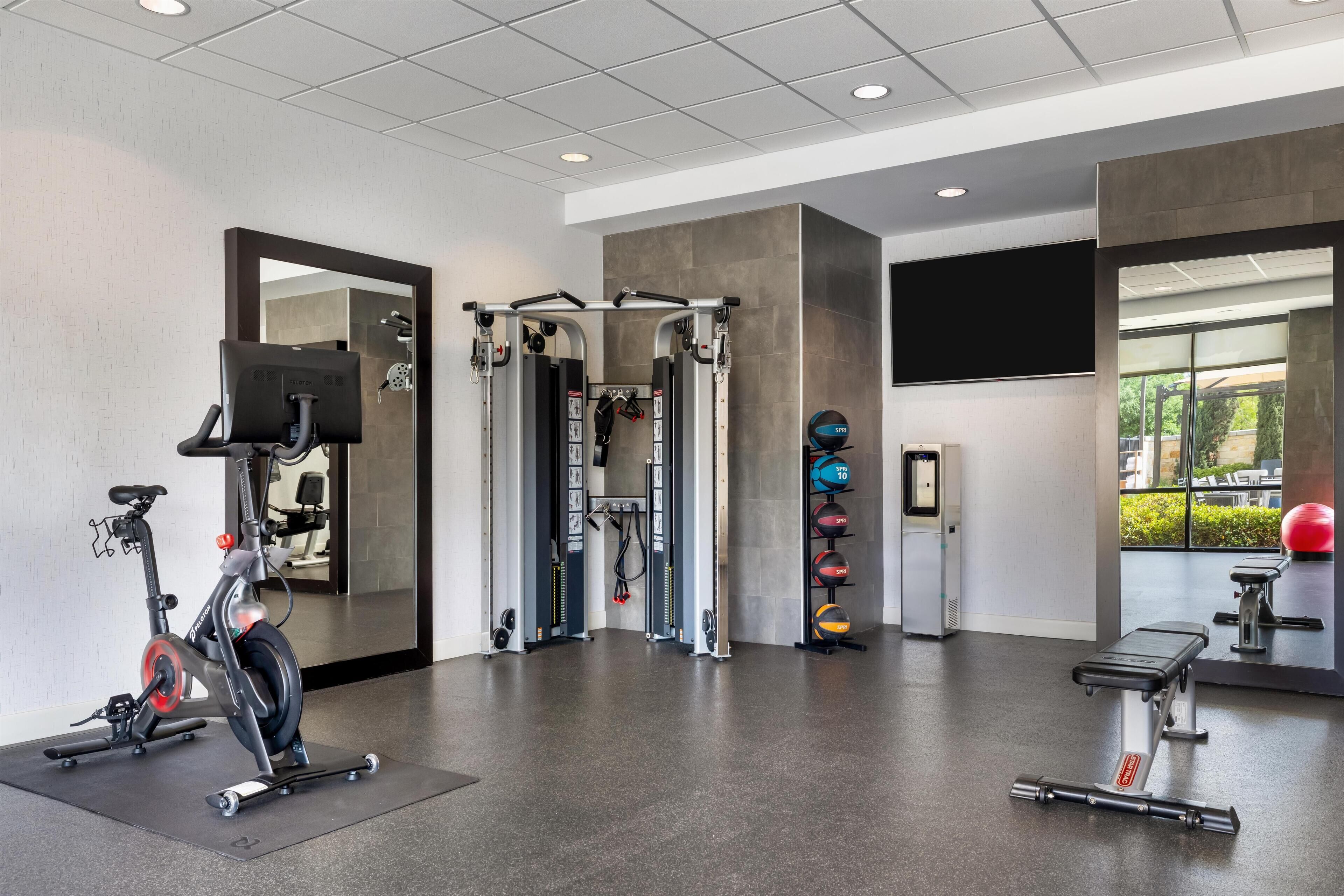 Un gimnasio con equipo de ejercicio, un espejo y una ventana con vistas.