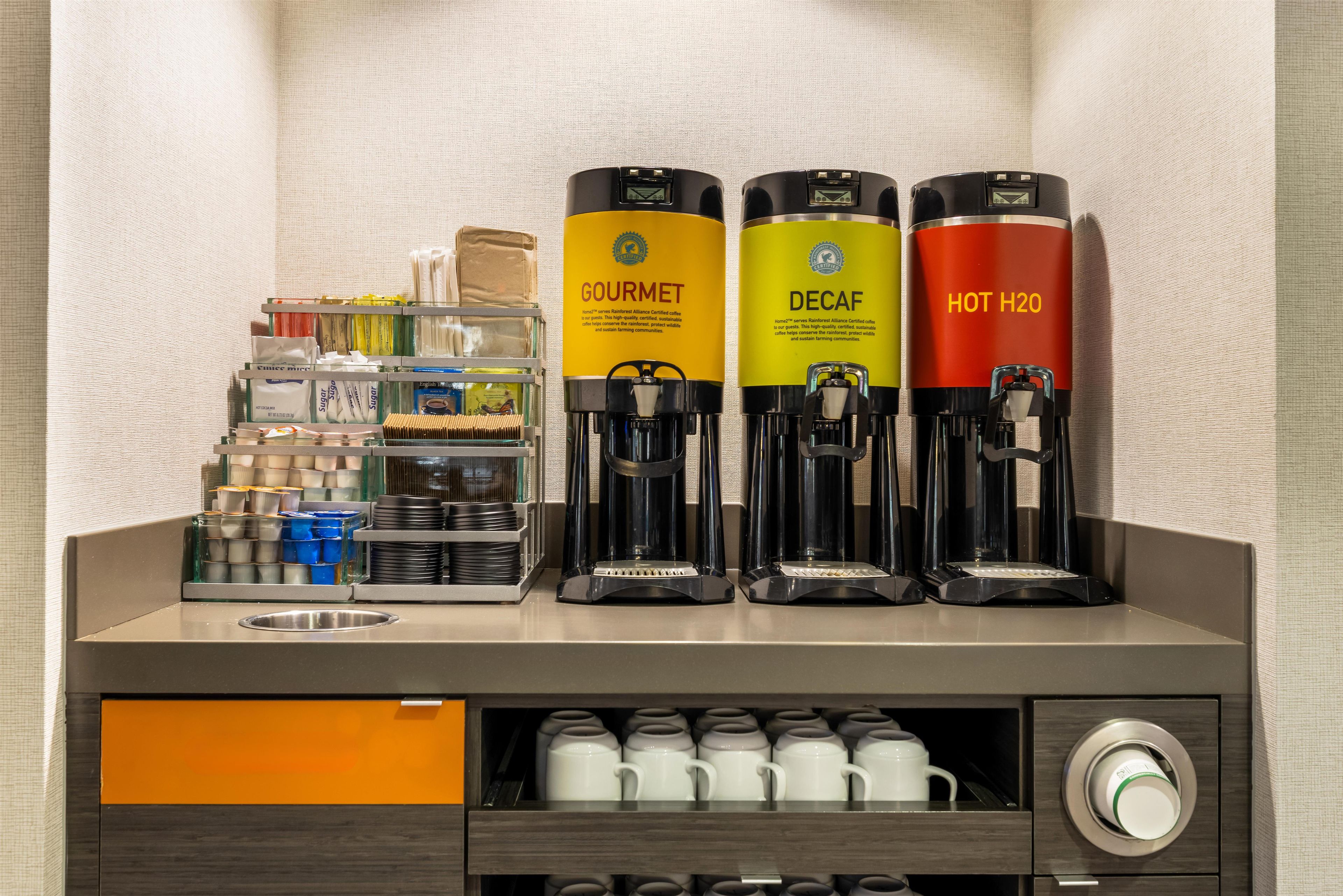 A coffee station with three coffee machines labeled 'GOURMET,' 'DECAF,' and 'HOT H2O.'