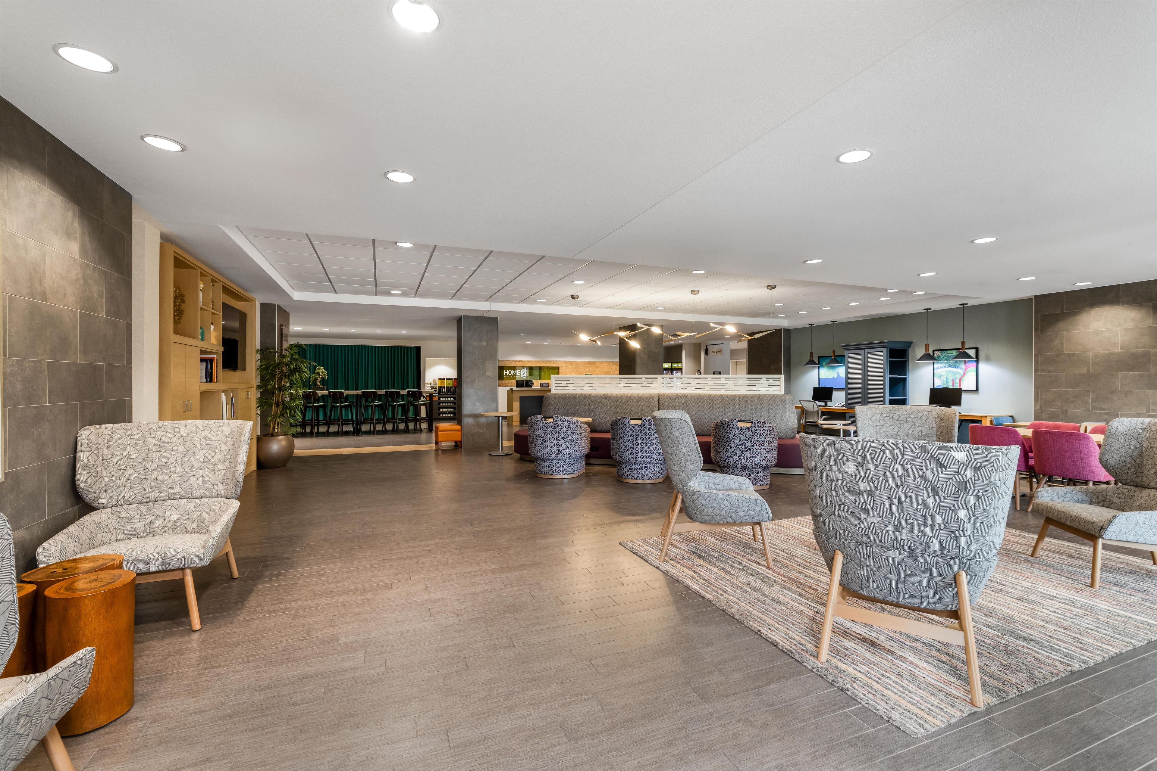 A modern lobby with seating areas, a reception desk, and a green curtain backdrop.