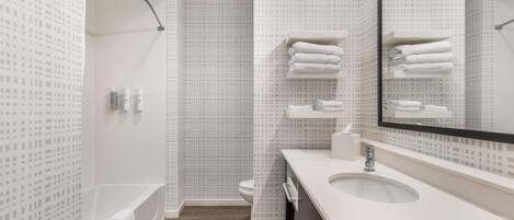 A modern bathroom with a bathtub, a toilet, and a sink with a mirror.