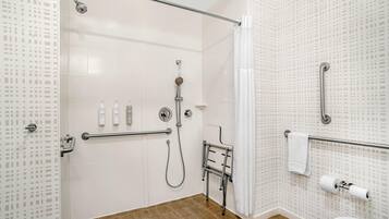 Un baño moderno con ducha, inodoro y barras de apoyo.
