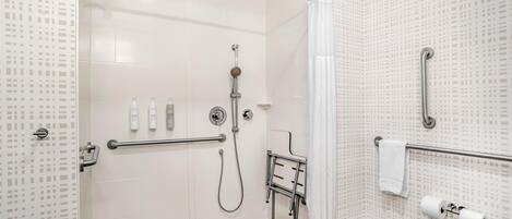 Un baño moderno con ducha, inodoro y barras de apoyo.