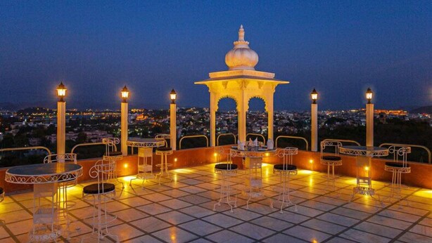 A terrace with tables and chairs, a decorative pavilion, and a cityscape view in the background. - Regenta Central Mewargarh Udaipur (Udaipur)