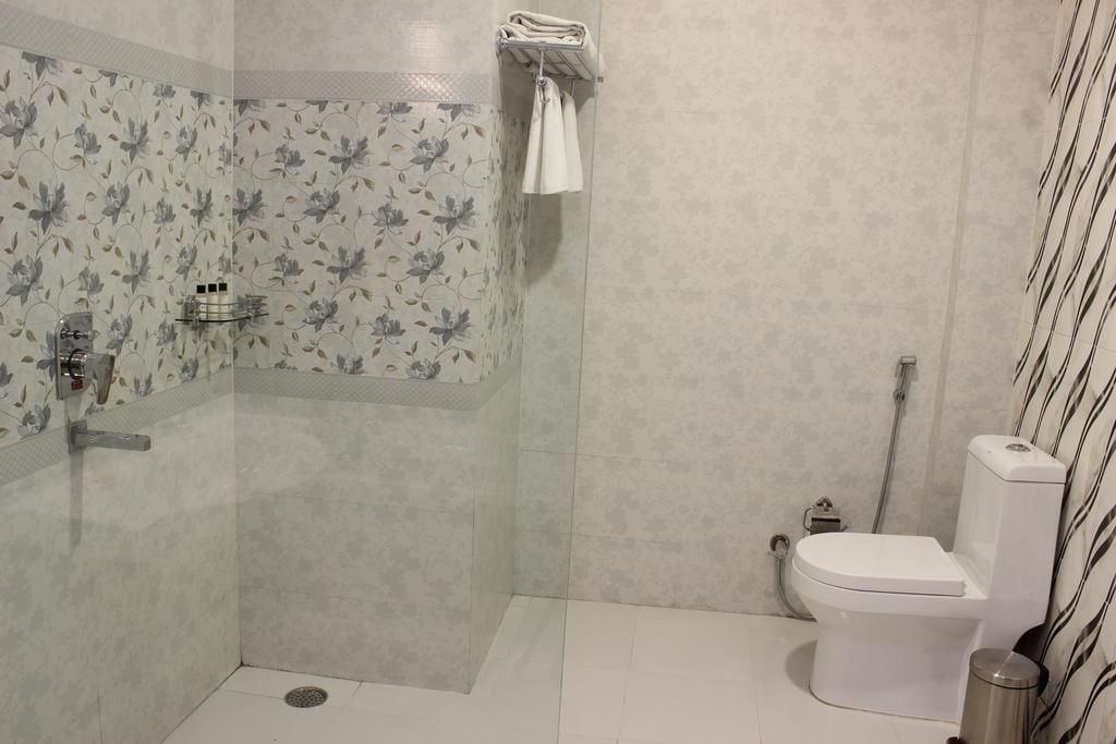 Et badeværelse med bruser, toilet og et brusekabine med glasvægge.