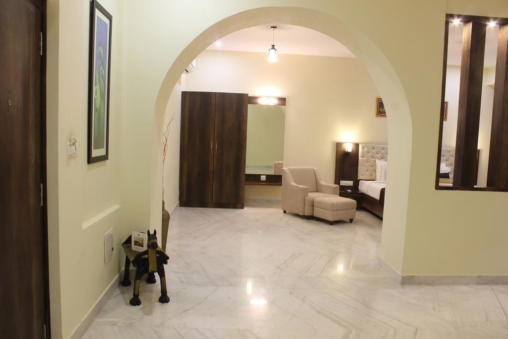 A spacious living area with a marble floor, a sofa, a chair, and a bed.