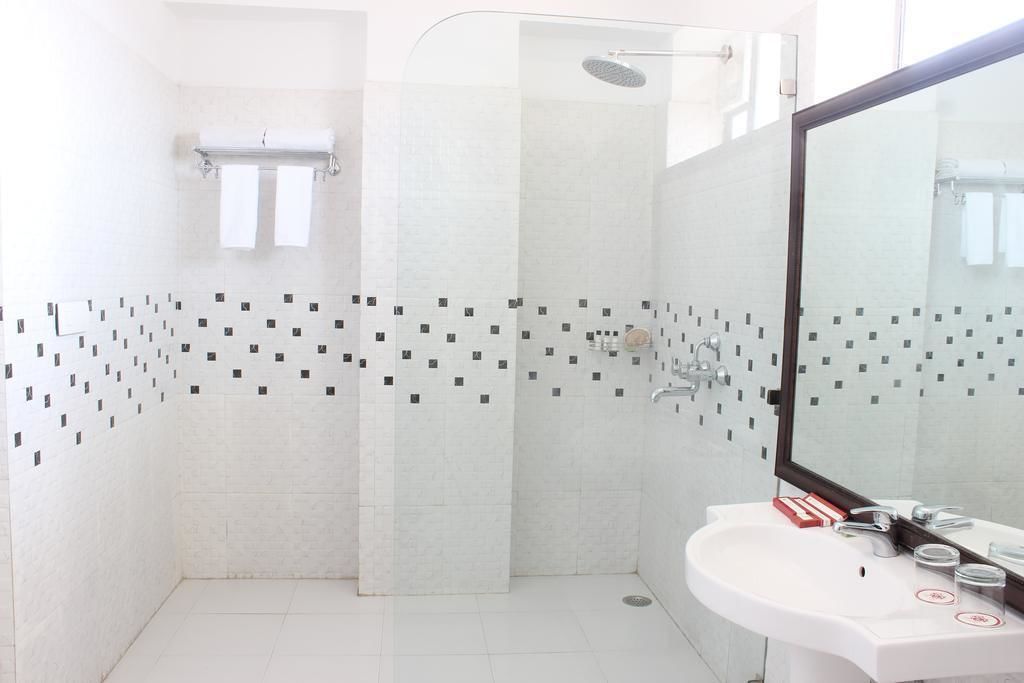 A modern bathroom with a shower, a sink, and a mirror.