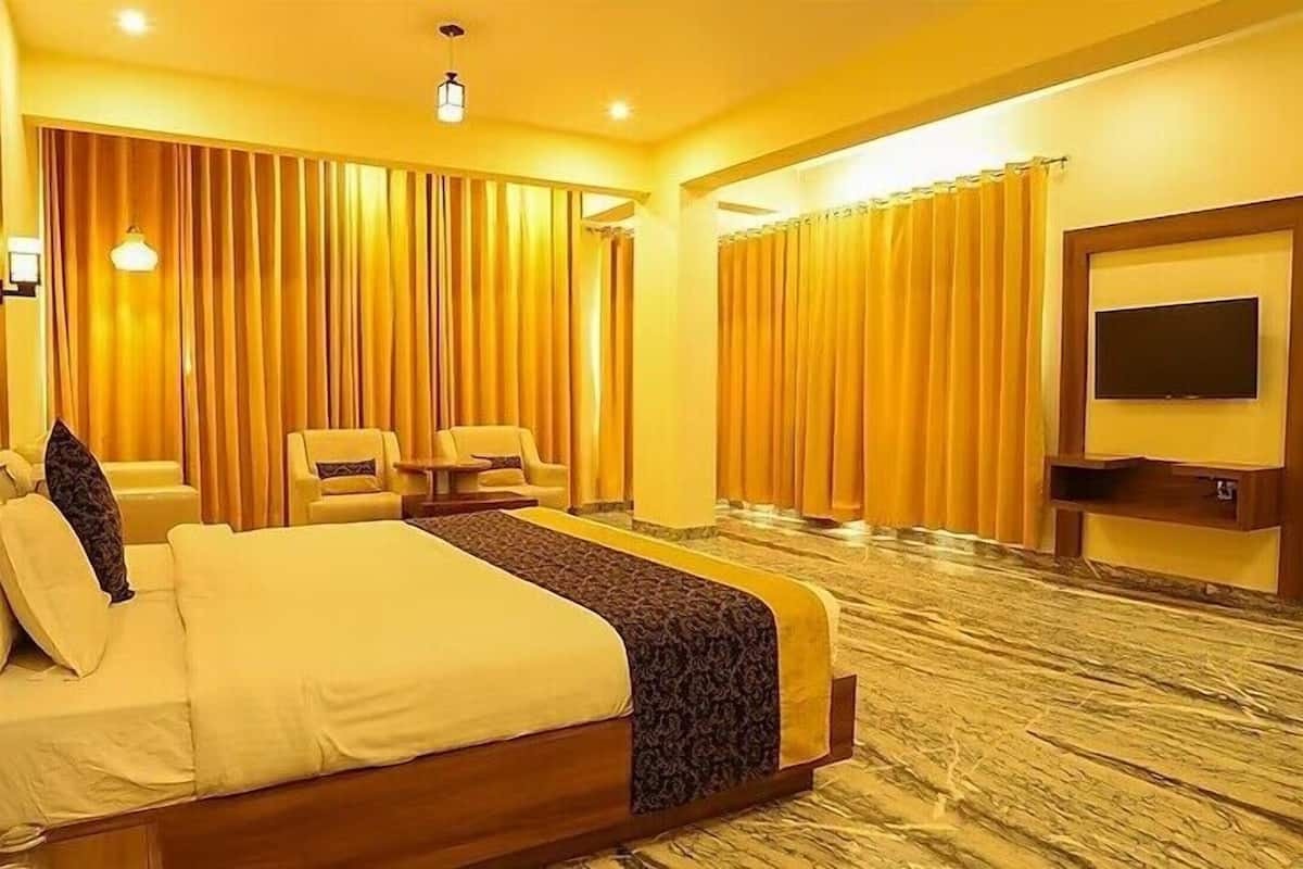 Une chambre d’hôtel avec un grand lit, une télévision, un bureau et deux chaises.