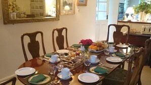 A dining table set for four with plates, cutlery, and a fruit basket. - Stone House Bed and Breakfast (Banbury)