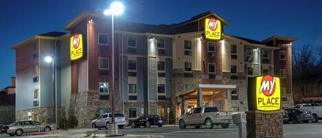 A multi-story hotel with 'My Place' signage, a parking lot, and a well-lit entrance.