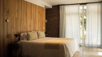 Un dormitorio con una pared de madera, una pared de ladrillo y un ventanal con cortinas.