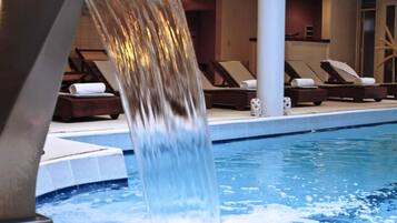 Una piscina amb cascada, gandules i zona de spa.
