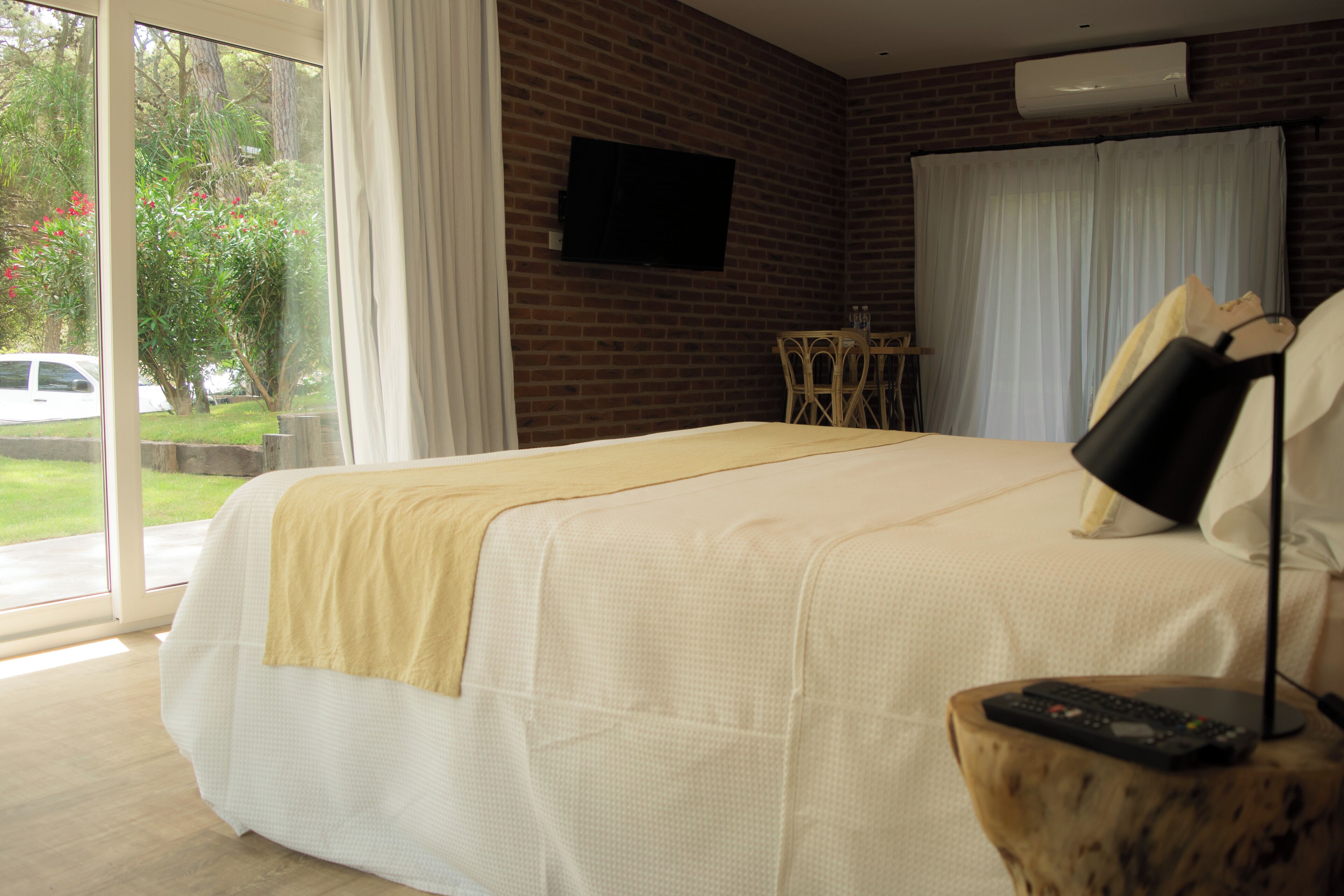 A hotel room with a large bed, a television on the wall, a small table, and a window with curtains.