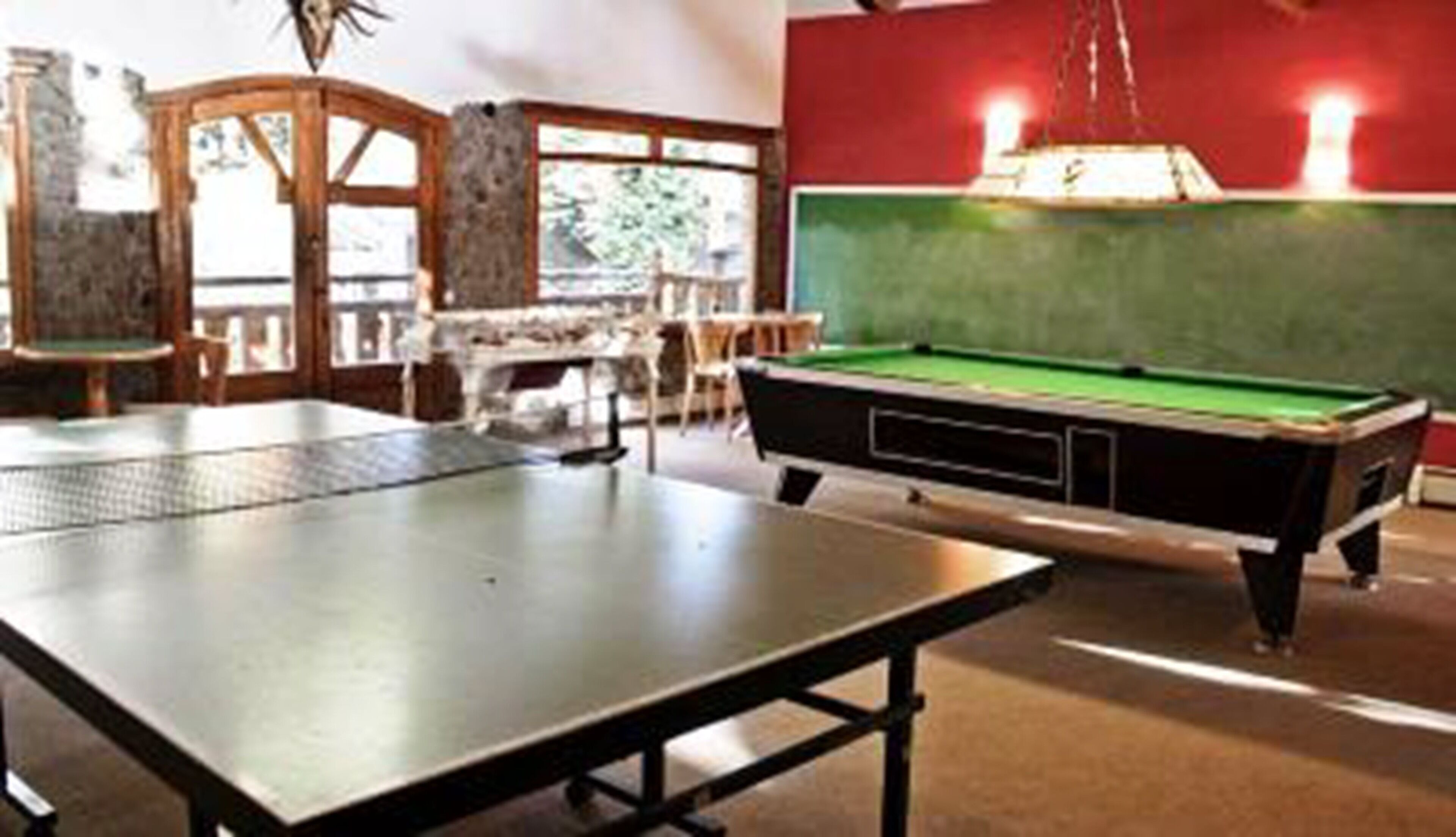 A billiards table with a green felt surface, a pool table, and a red wall in the background.