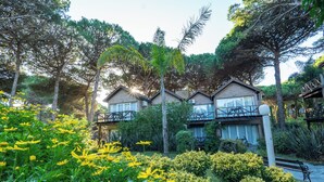 A residential building with multiple balconies, surrounded by lush greenery and flowering plants. - Carilo Village Apart Hotel & Spa (Carilo)